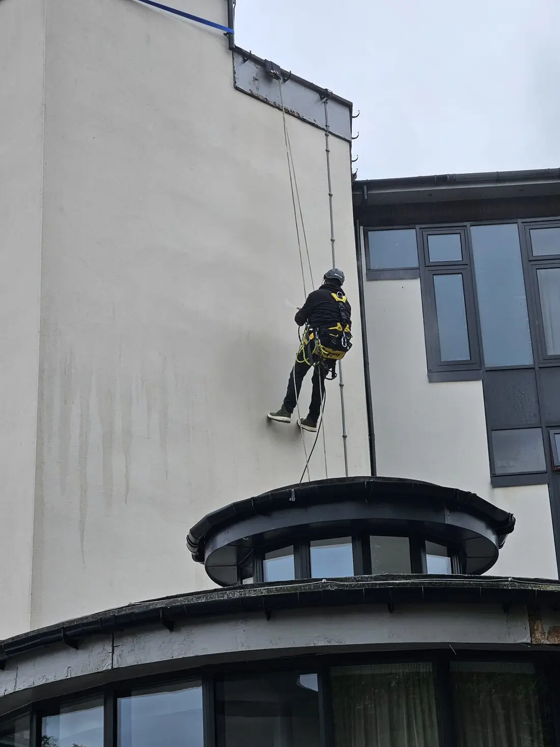Technician cleaning gutters and roofline using rope access