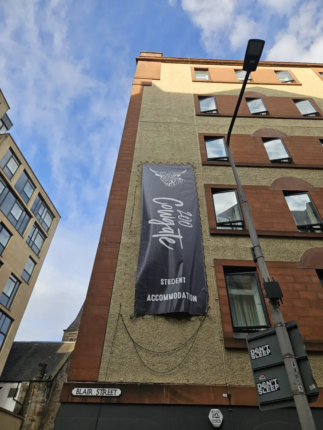 Technicians installing signage on a tall building using rope access